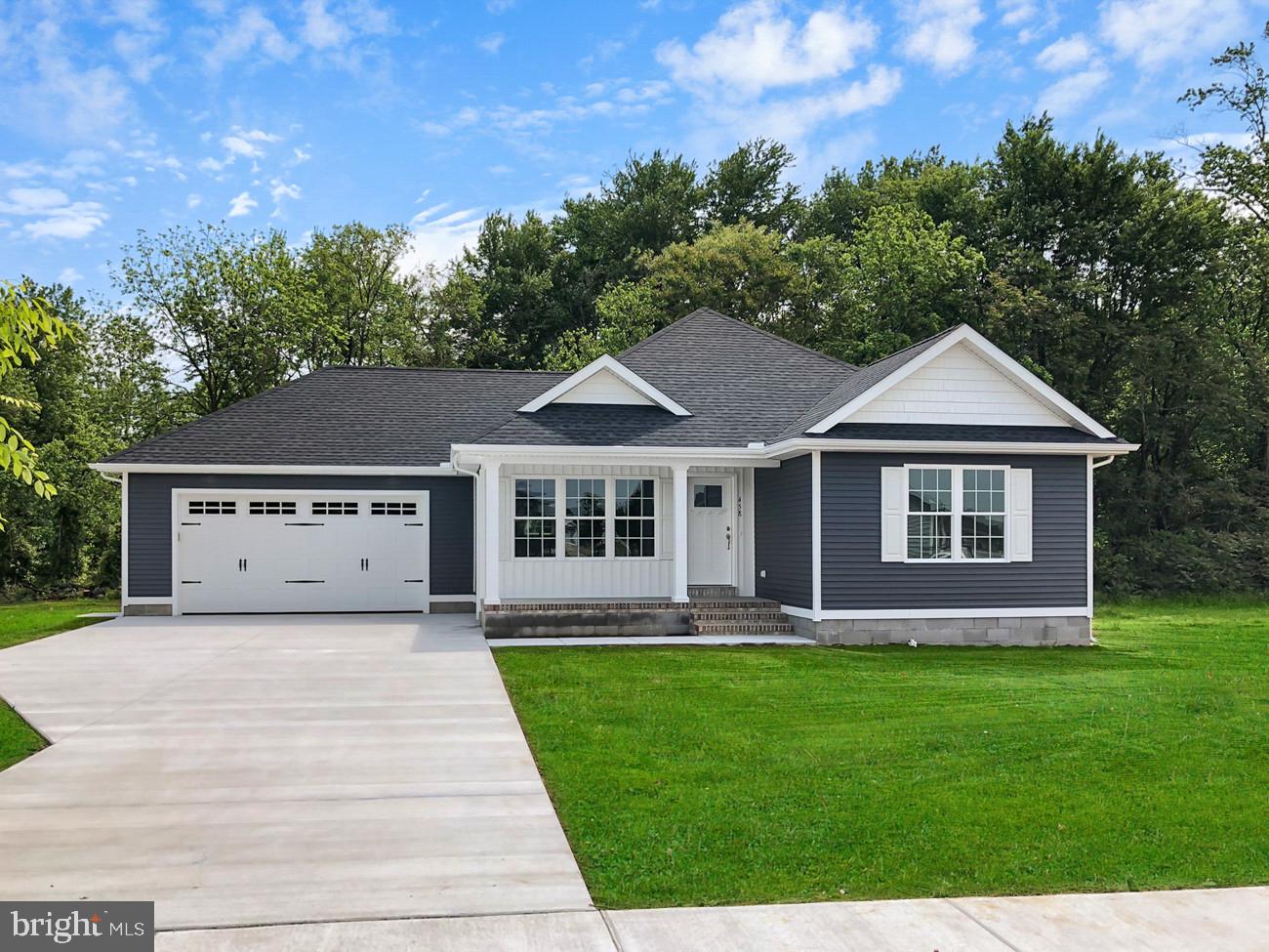 a front view of a house with a yard and trees