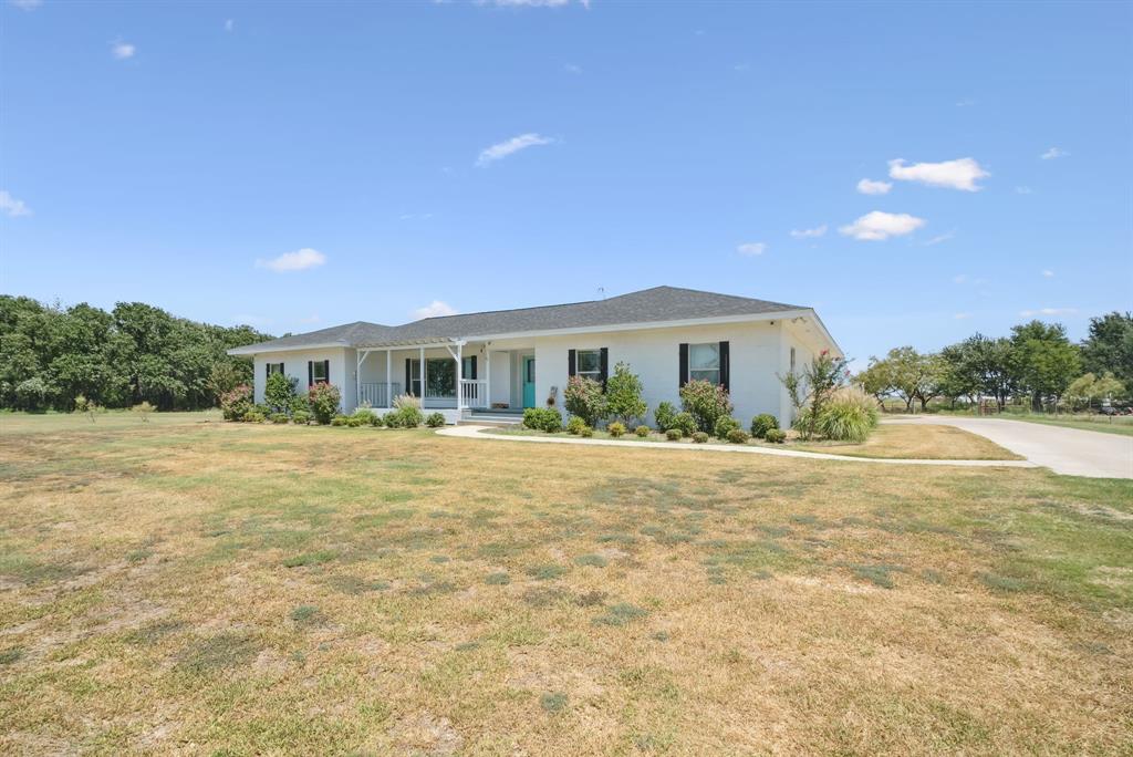 a front view of house with yard and trees in the background