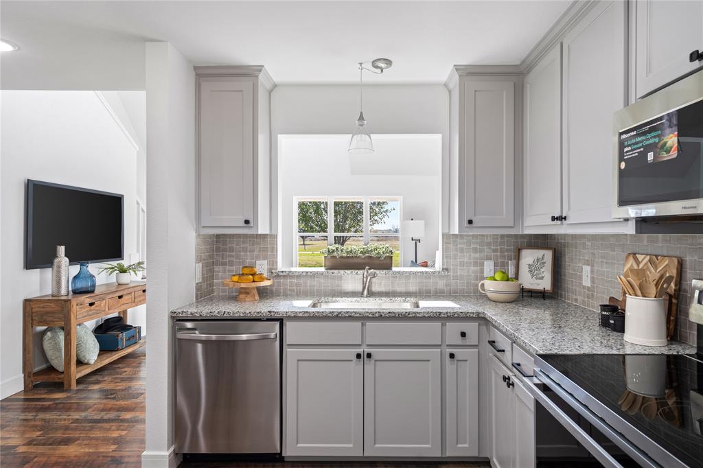 Kitchen featuring sink, dark hardwood / wood-style floors, gray cabinets, light stone countertops, and appliances with stainless steel finishes