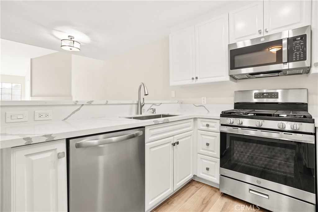 a kitchen with stainless steel appliances a stove microwave and sink