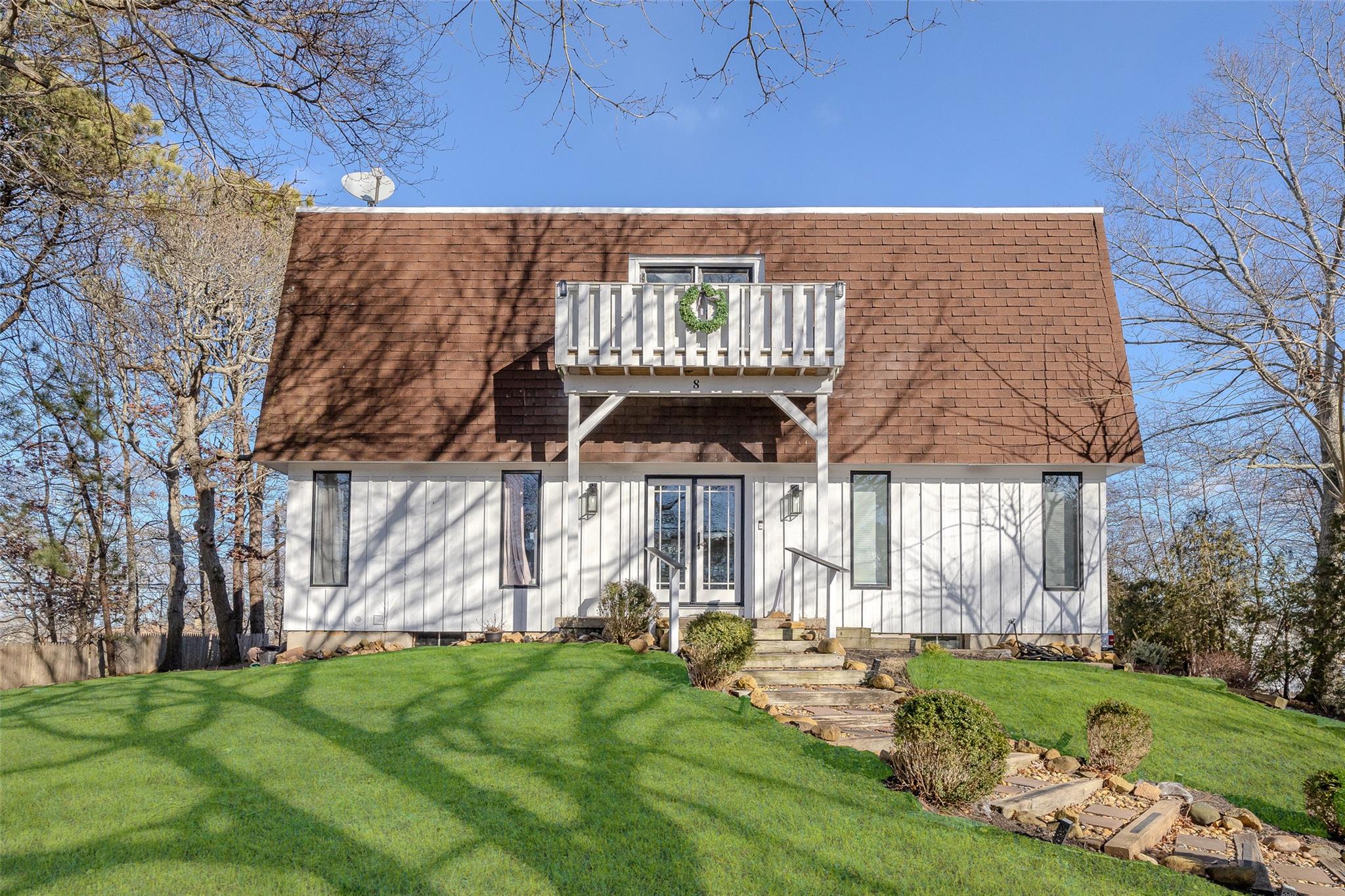 View of front of house featuring a balcony and a front lawn