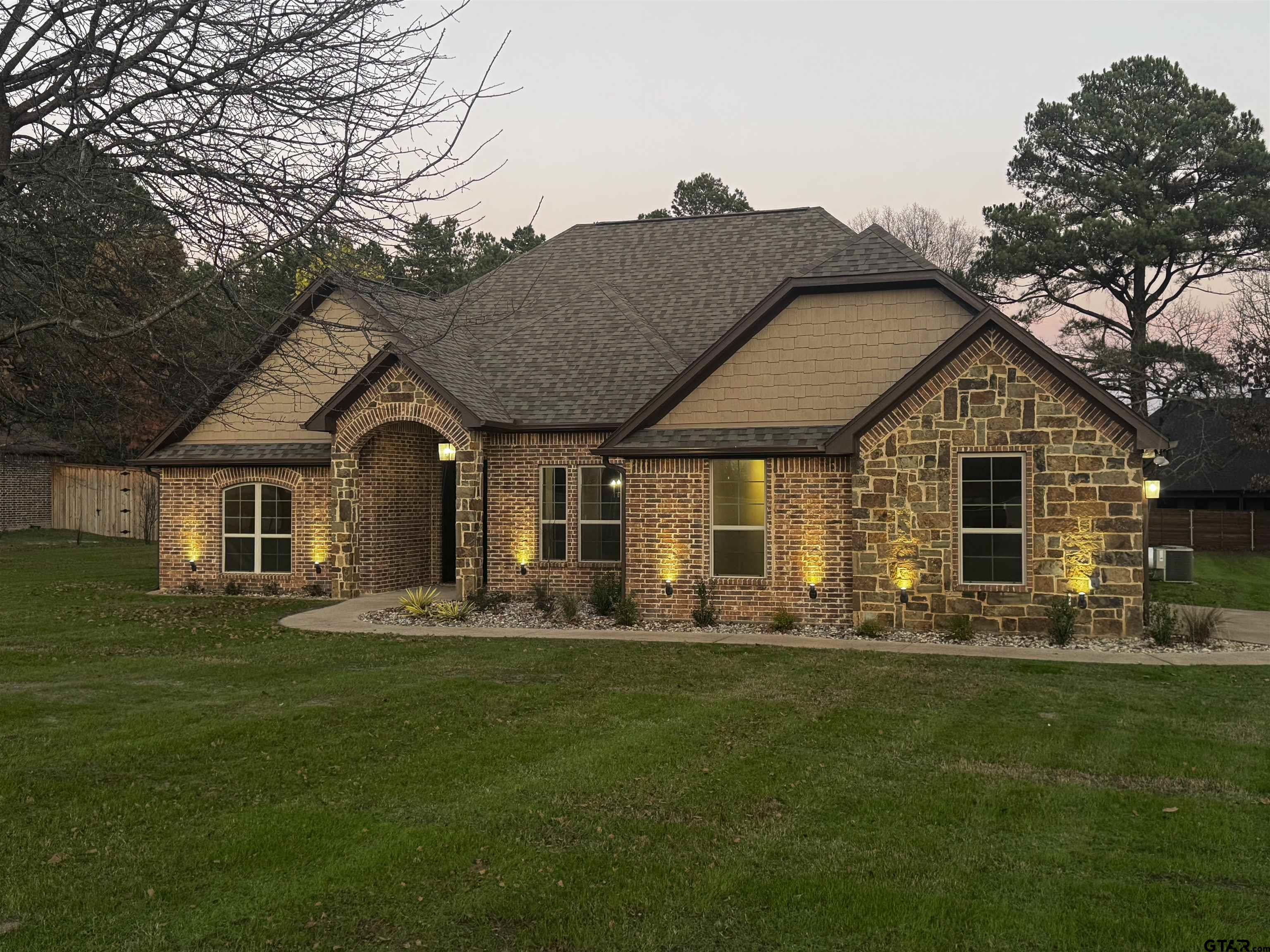 a front view of a house with a garden and trees