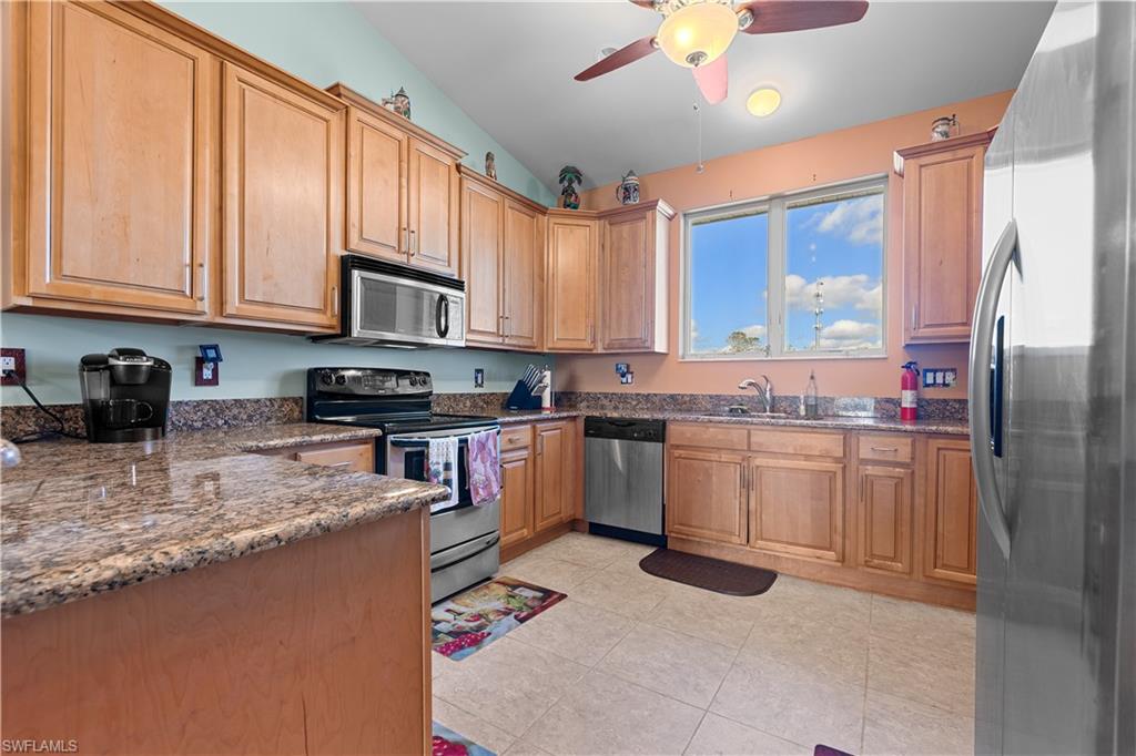 a kitchen with granite countertop a sink stainless steel appliances and cabinets