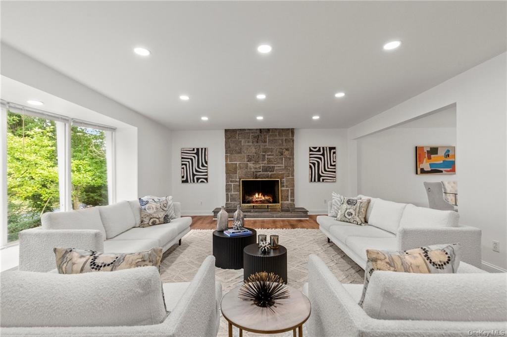 Living room with a stone fireplace and light hardwood / wood-style floors