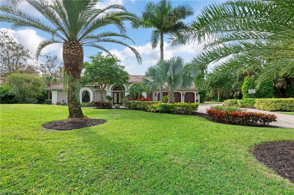 a front view of a house with garden and trees