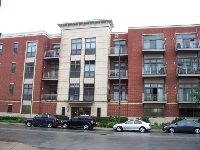 a front view of a building with lot of cars and trees