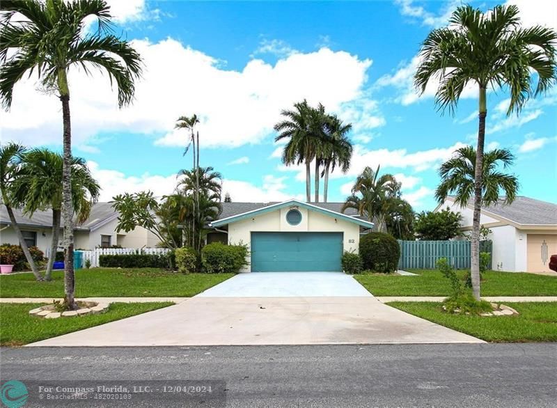 a white house with a yard and palm trees