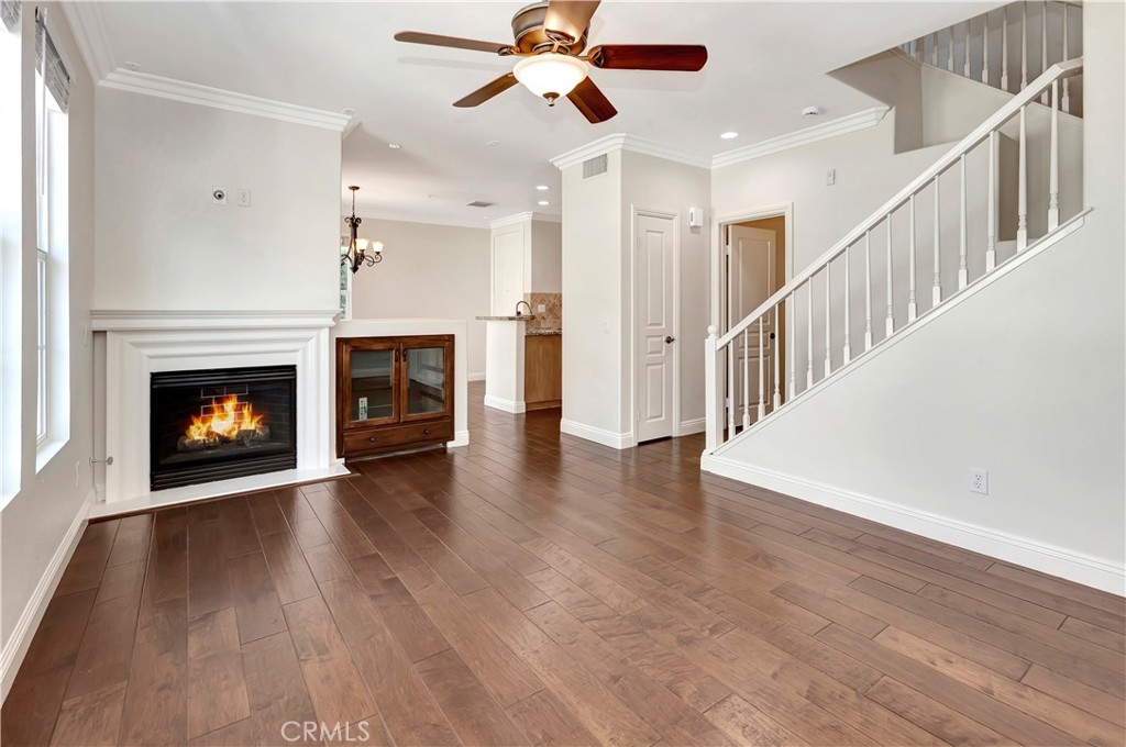 a view of an empty room with wooden floor fireplace and a window