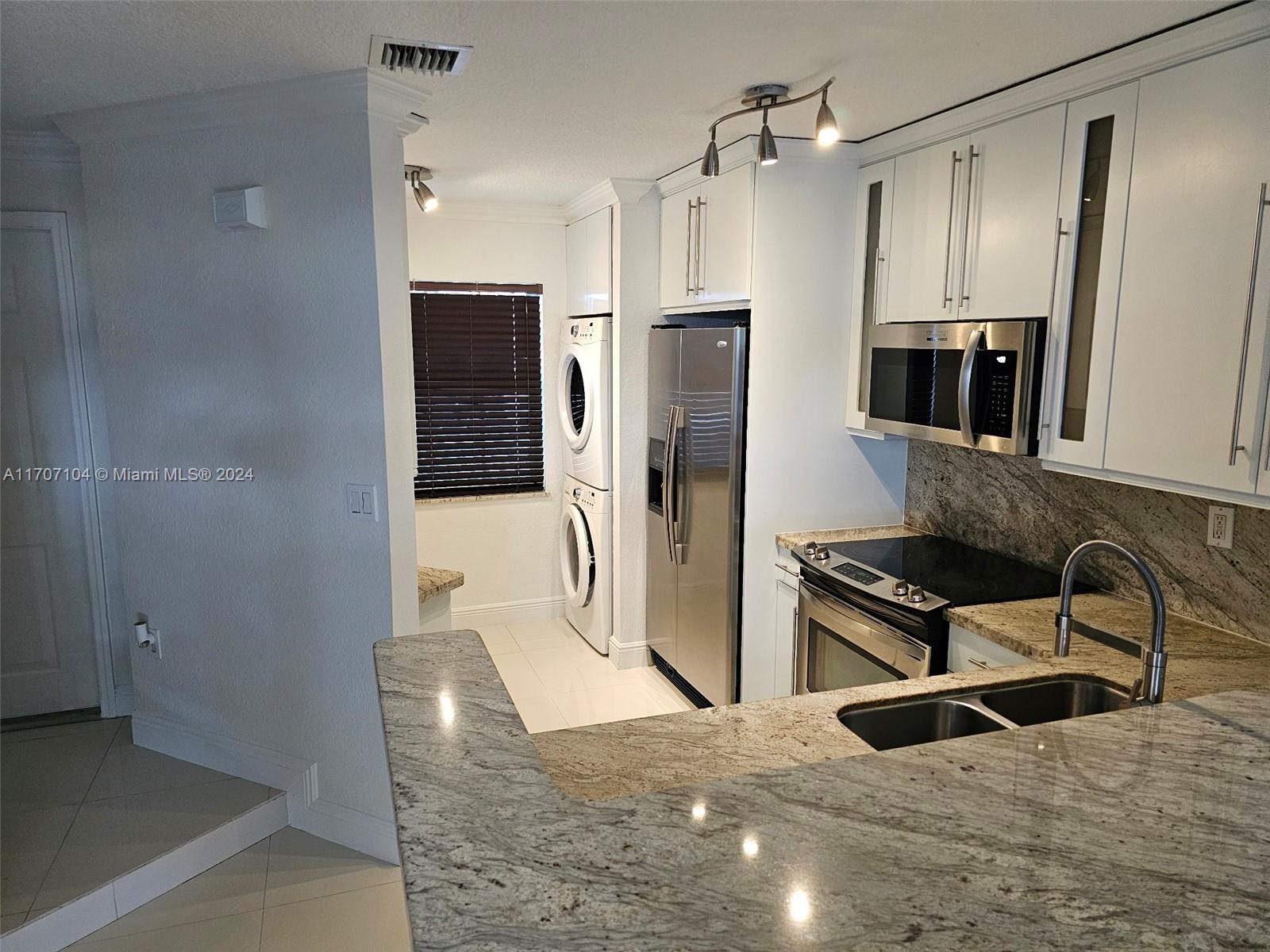 a kitchen with granite countertop a refrigerator and a sink