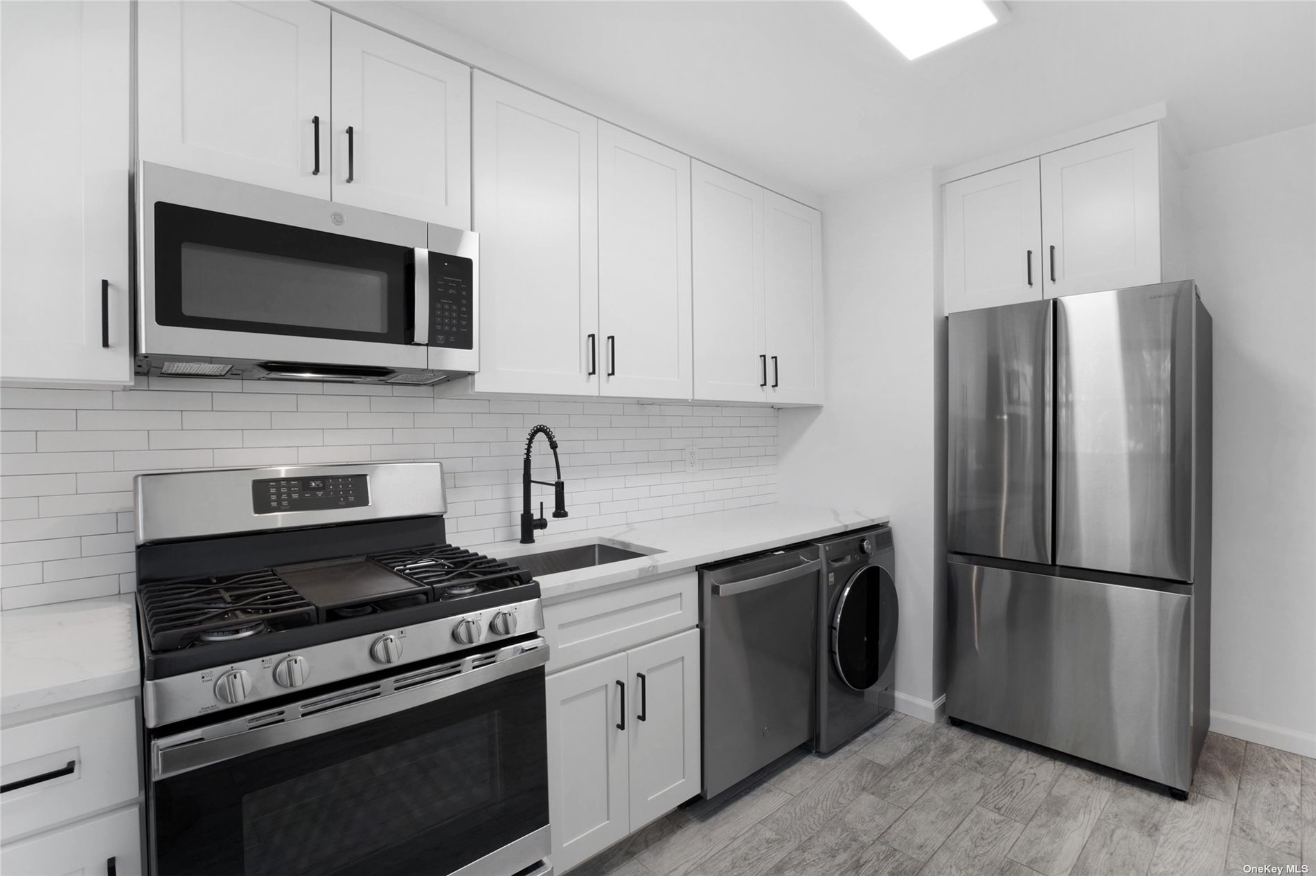 a kitchen with cabinets stainless steel appliances and a wooden floor