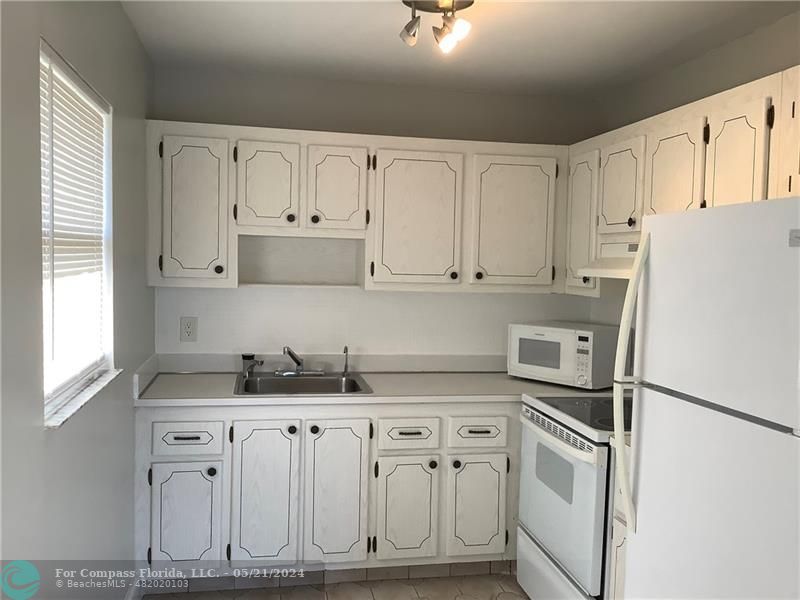 a kitchen with granite countertop white cabinets and refrigerator