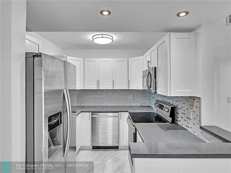 a kitchen with stainless steel appliances granite countertop a sink a stove and a refrigerator