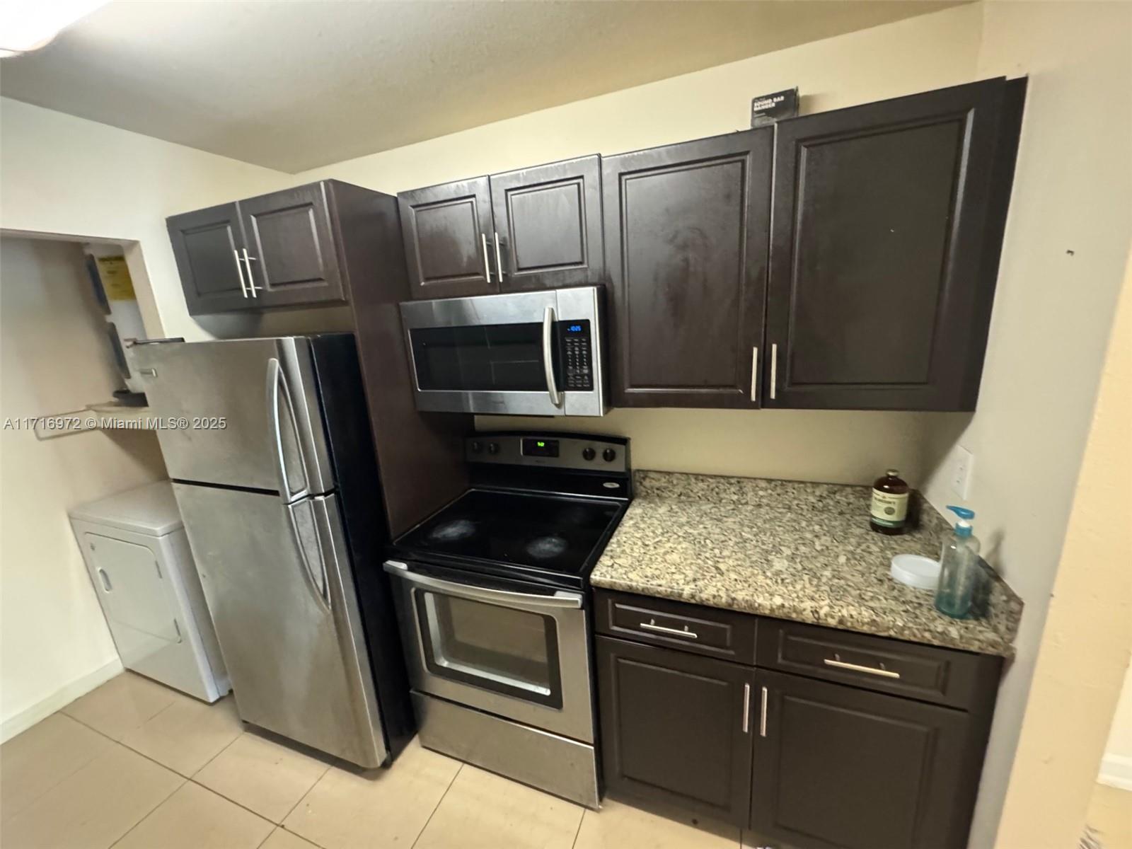 a kitchen with granite countertop a refrigerator stove and microwave