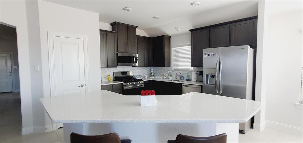 a kitchen with stainless steel appliances a refrigerator a sink a stove a microwave and island