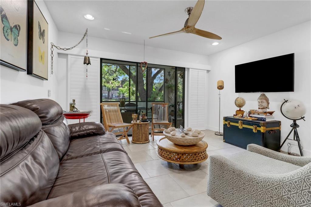 Living room with tiled floors, plantation shutters, access to lanai overlooking lake/water feature and upgraded ceiling fan