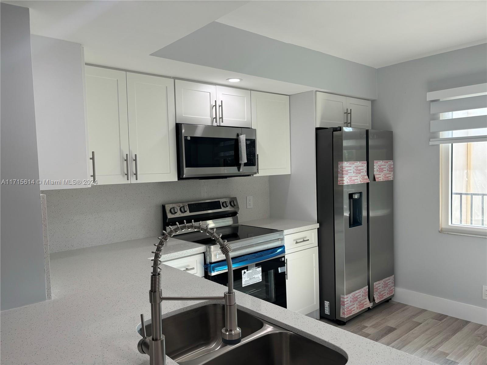 a kitchen with stainless steel appliances a refrigerator microwave and sink