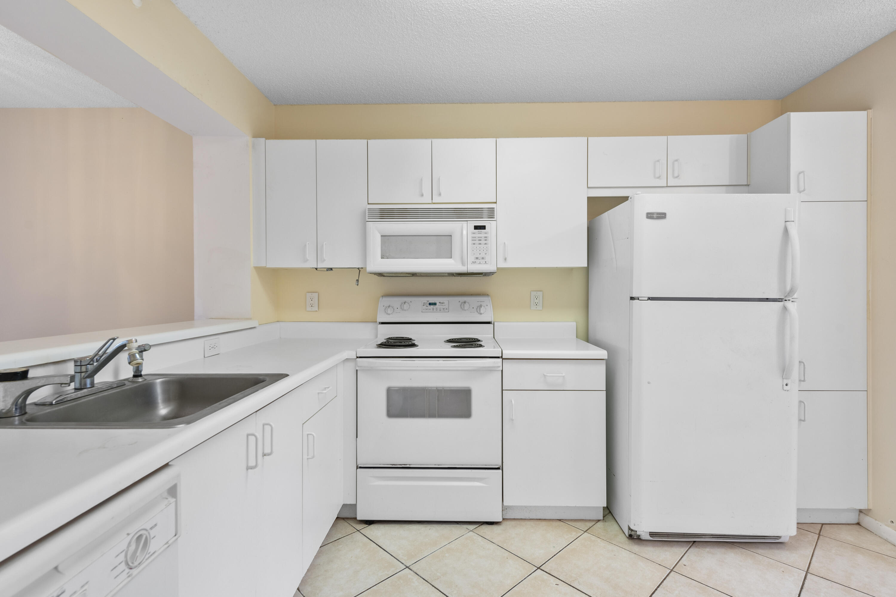 a kitchen with cabinets appliances a sink and a refrigerator