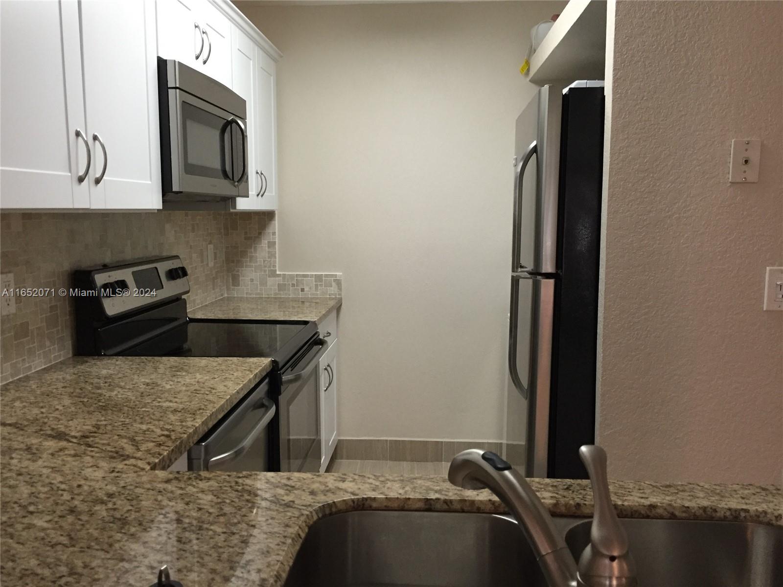 a kitchen with a granite countertop sink stainless steel appliances and cabinets