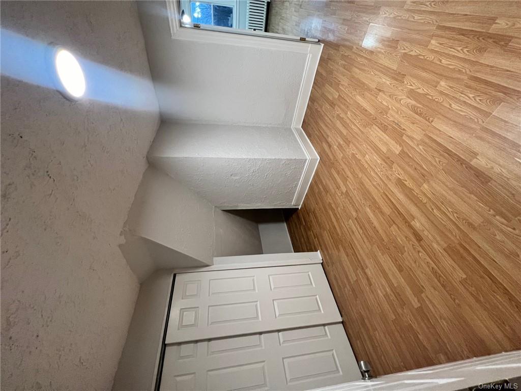 Bonus room featuring a textured ceiling, vaulted ceiling, radiator heating unit, and light hardwood / wood-style floors