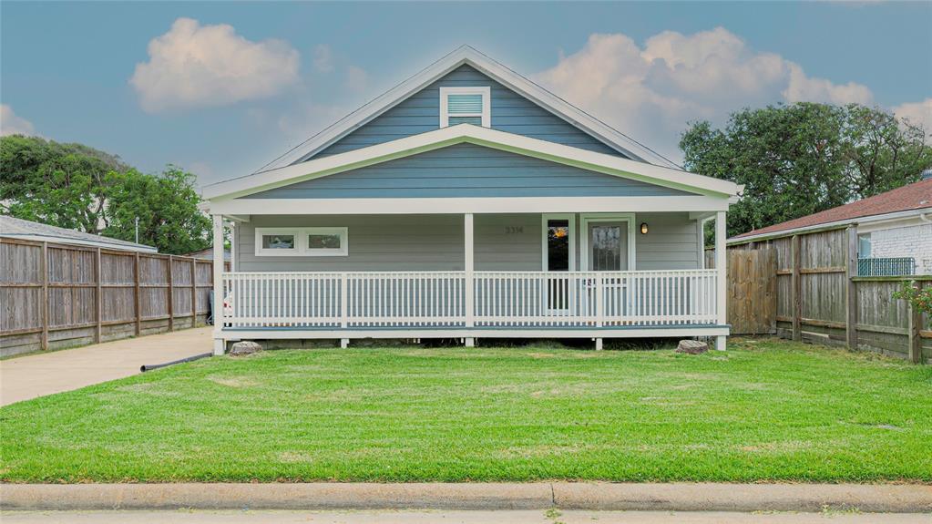 a view of a house with a yard and a large tree