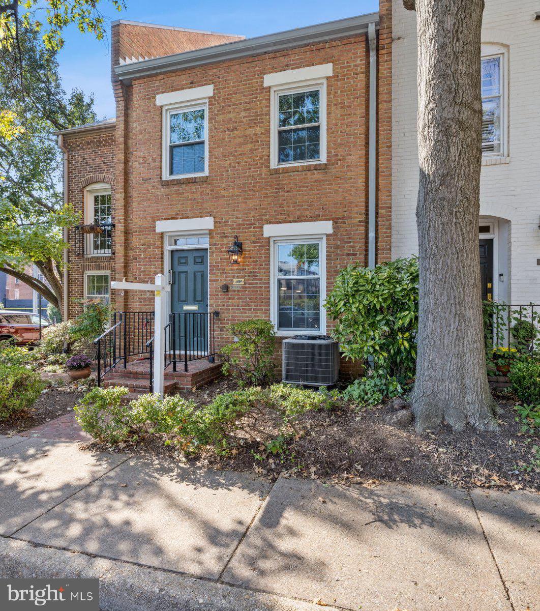 a view of a brick house with a yard and large tree