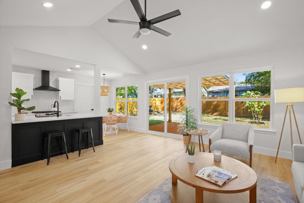 a living room with stainless steel appliances kitchen island granite countertop a table chairs and a refrigerator