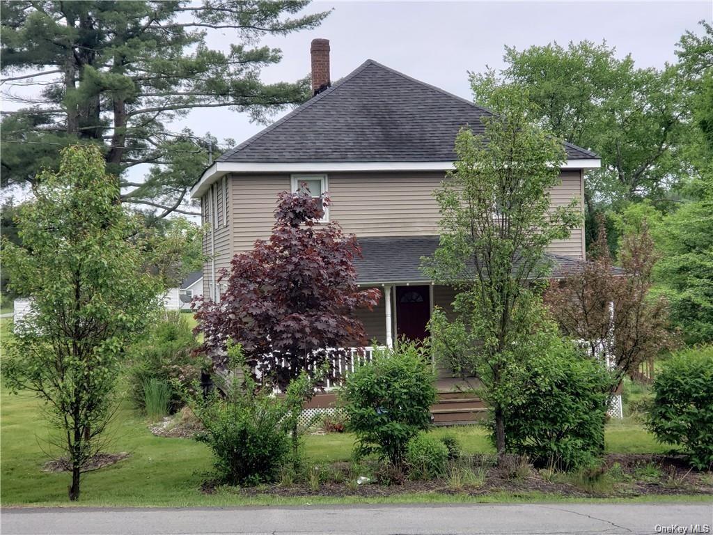 a front view of house with trees and flowers around