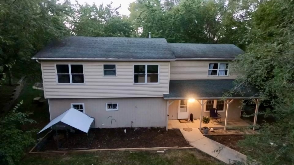 a aerial view of a house with yard and trees in the background