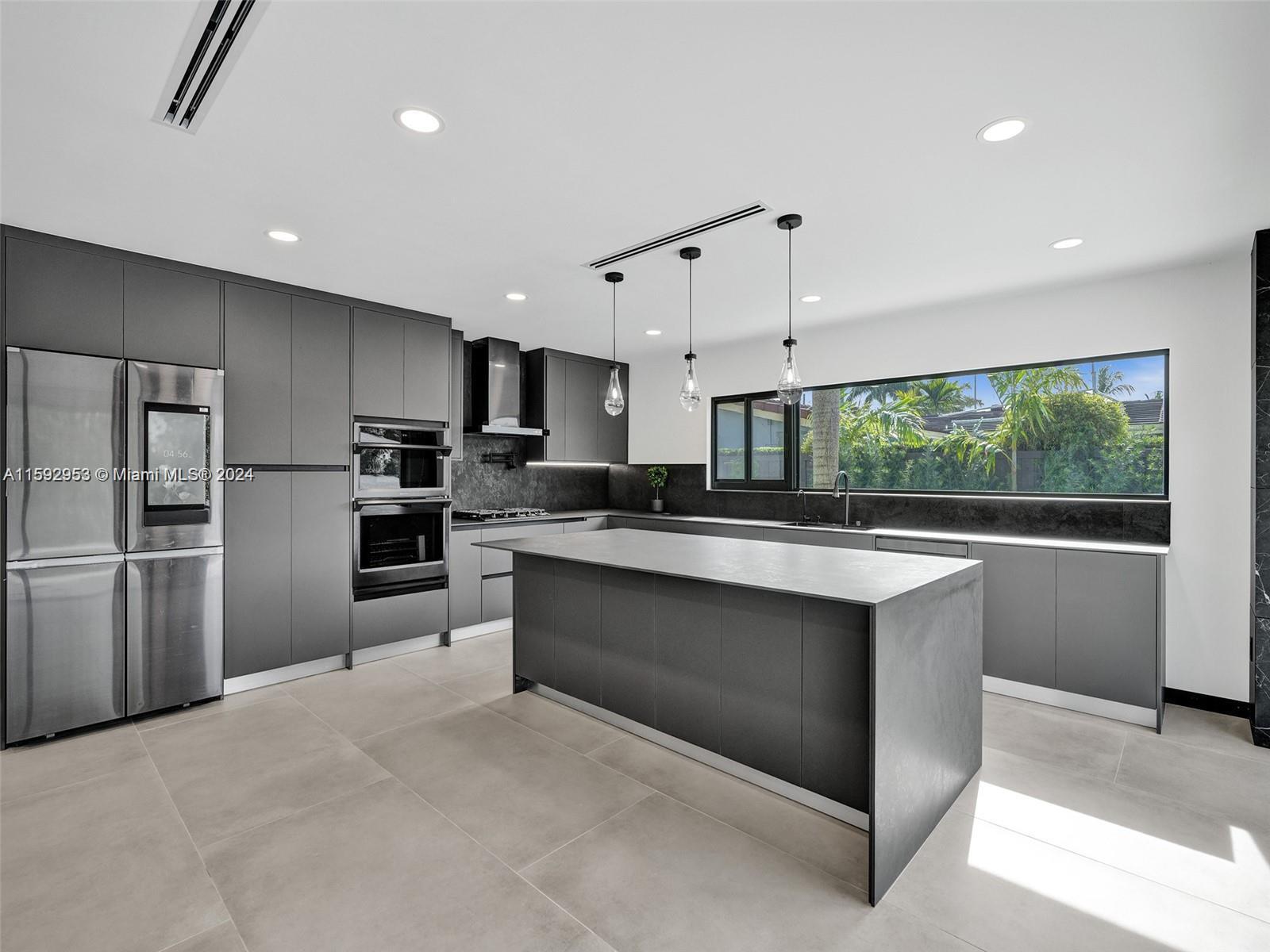 a large kitchen with kitchen island a large counter top stainless steel appliances and cabinets