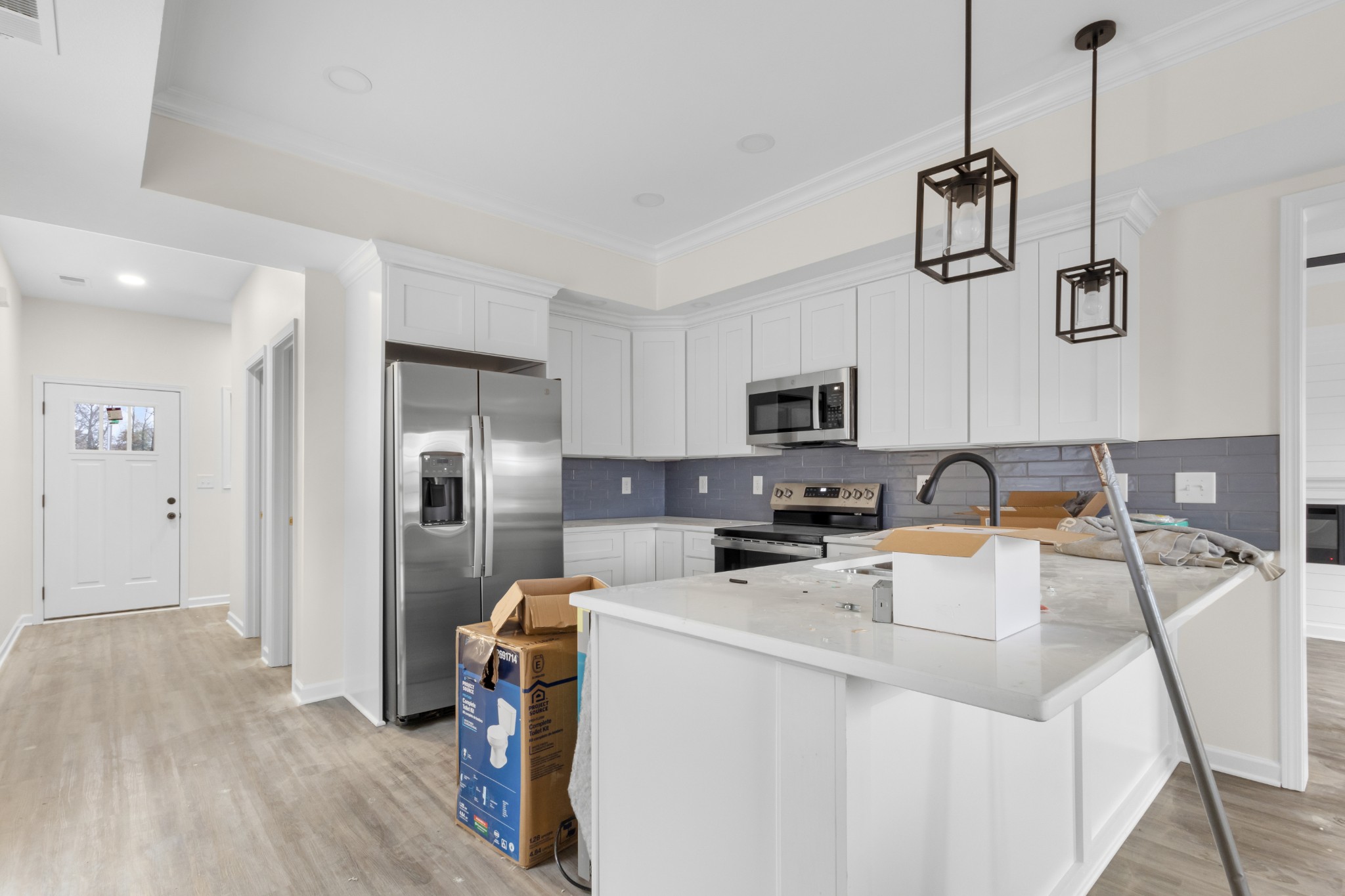 a living room with stainless steel appliances lots of furniture and wooden floor