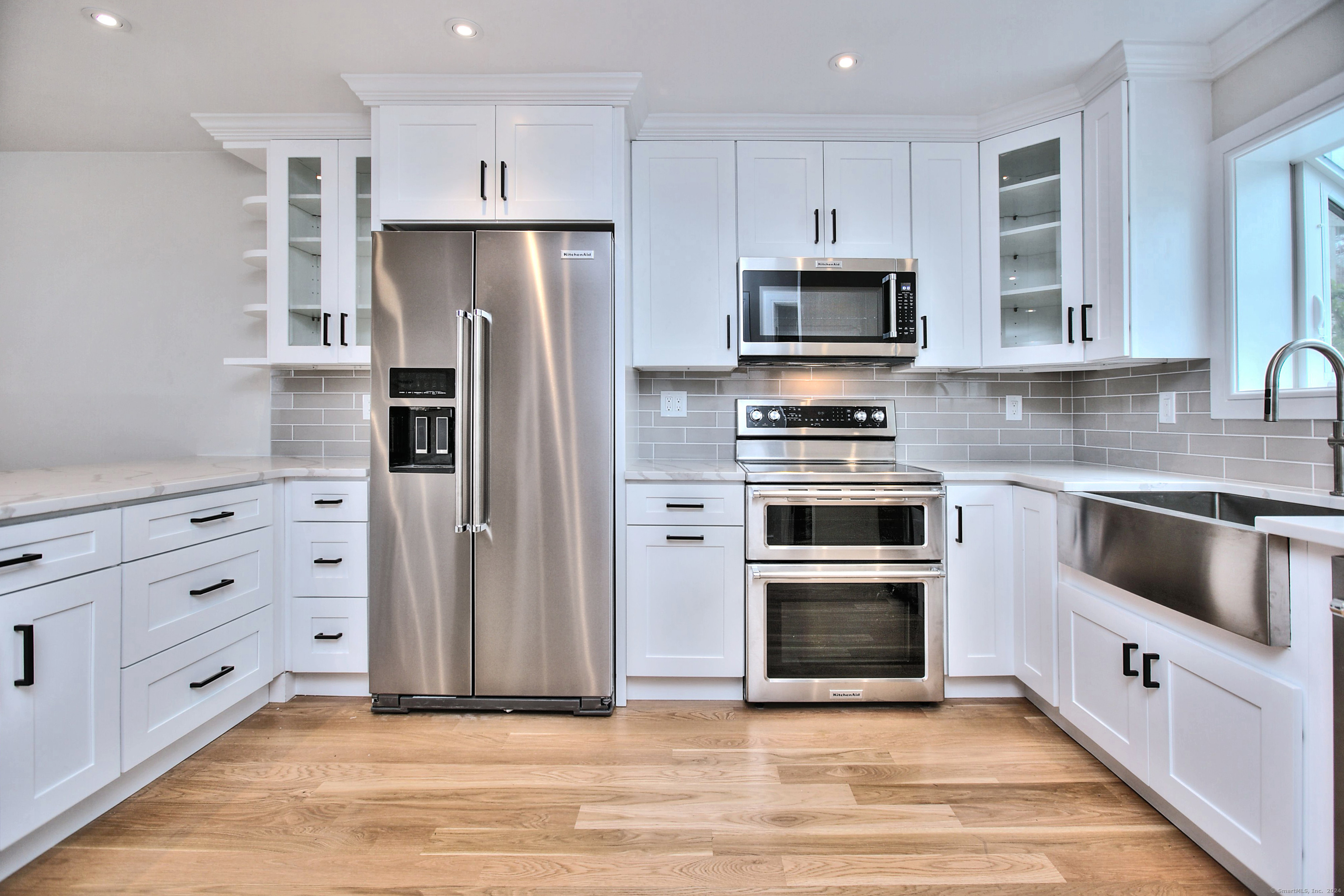 a kitchen with cabinets stainless steel appliances and wooden floor