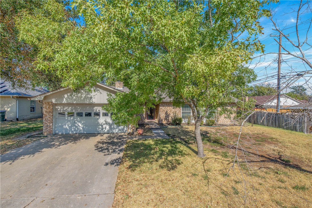 a view of a house with a yard and large tree