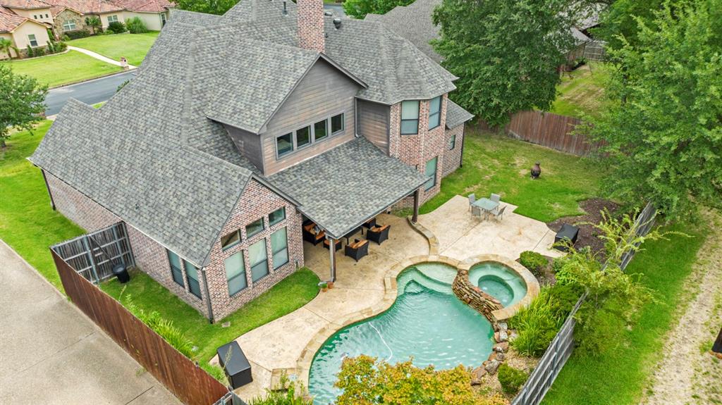 an aerial view of a house with swimming pool and large trees