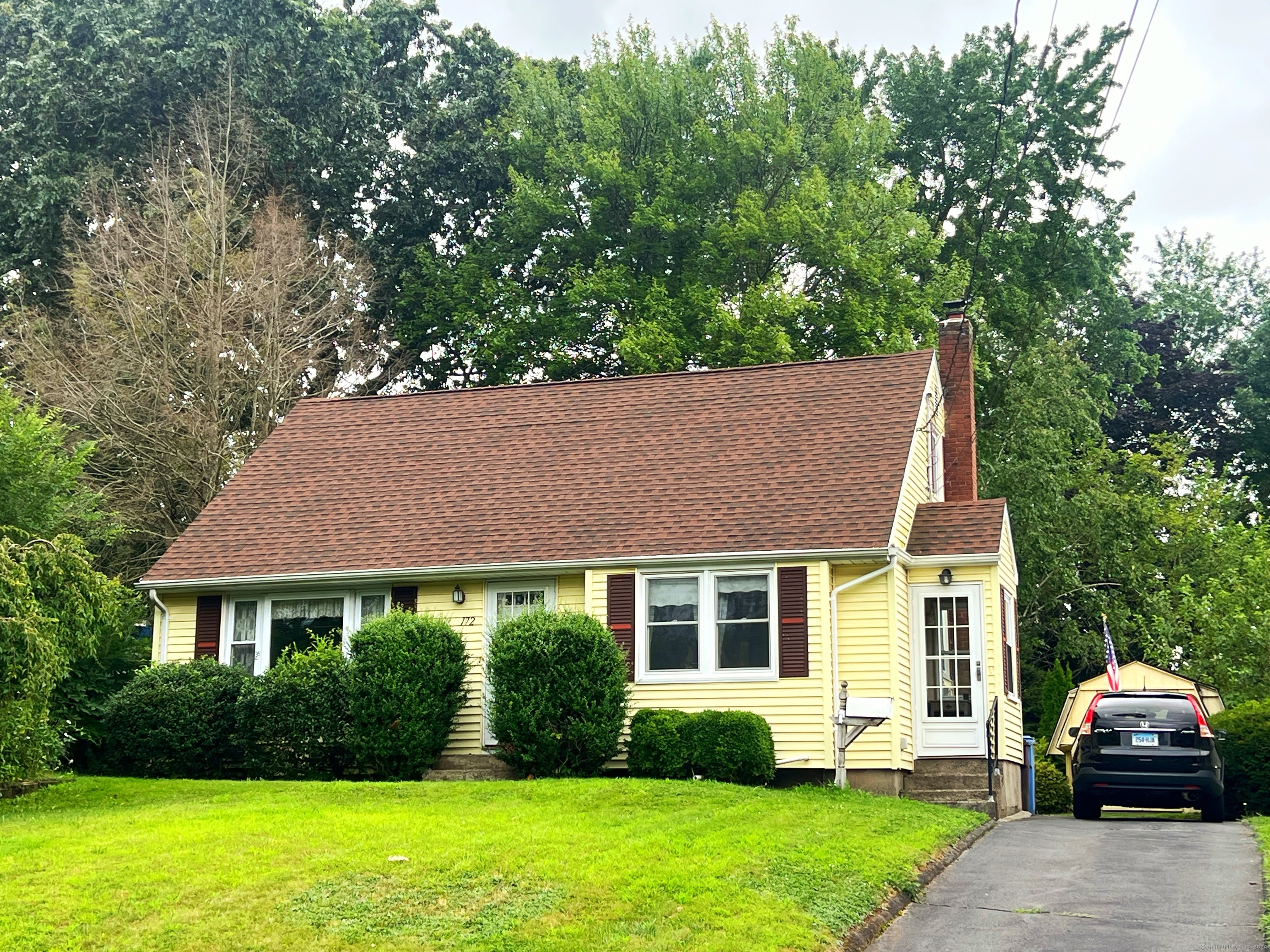 a front view of a house with a yard and trees