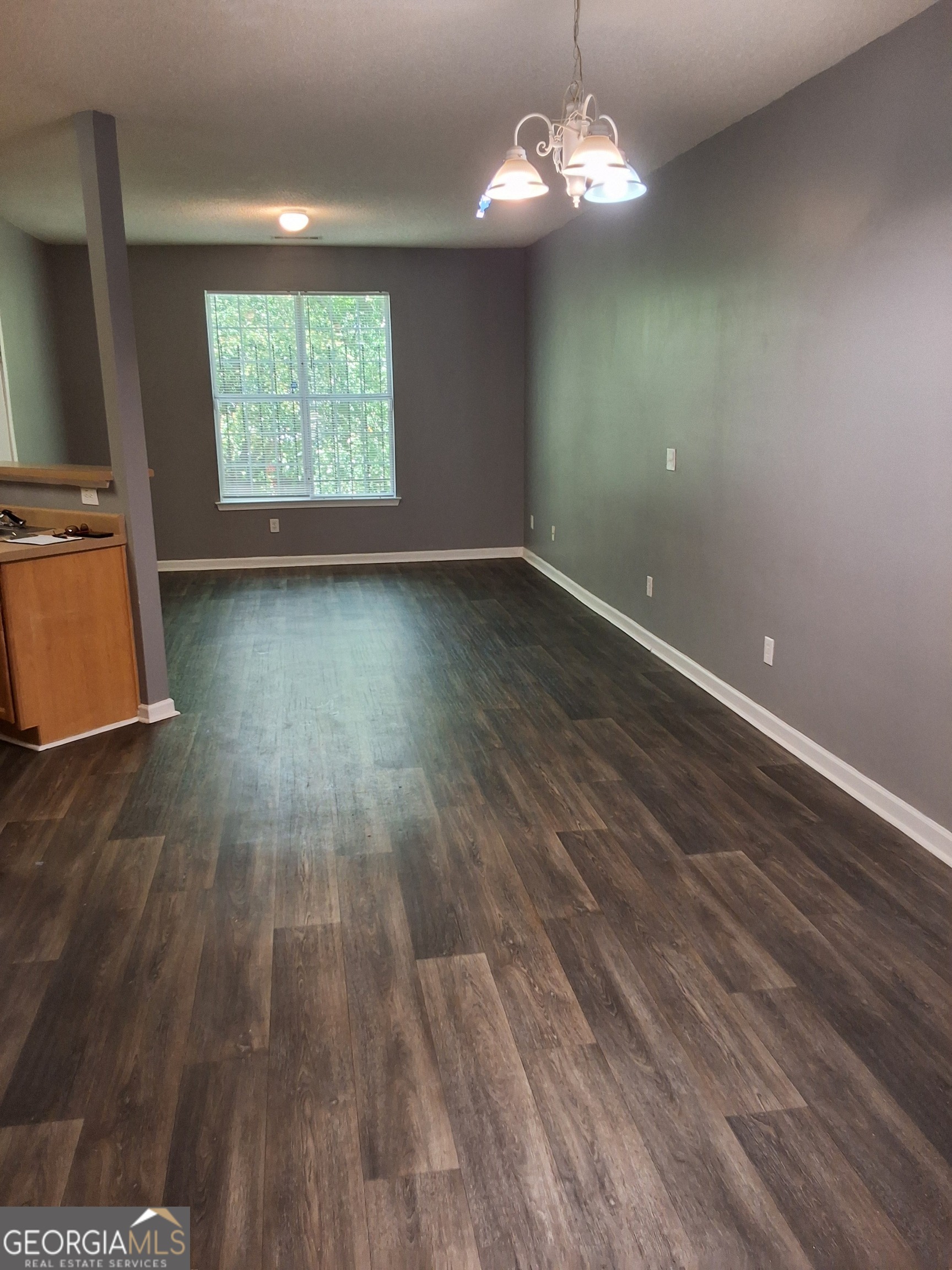 a view of a room with wooden floor and chandelier