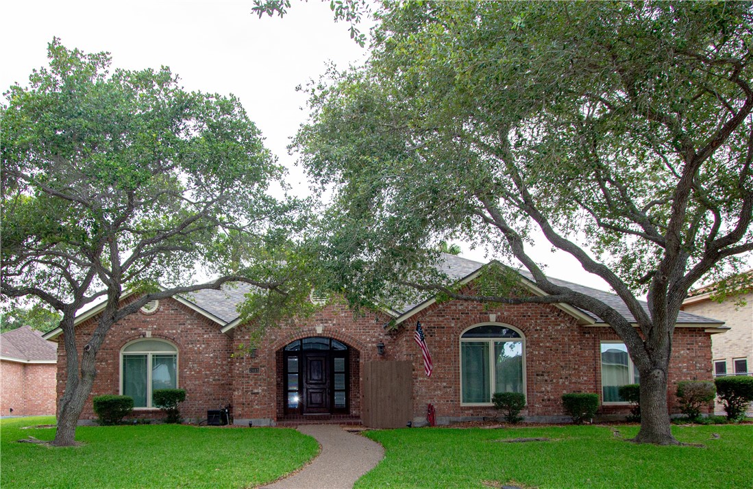 a front view of a house with a garden and trees