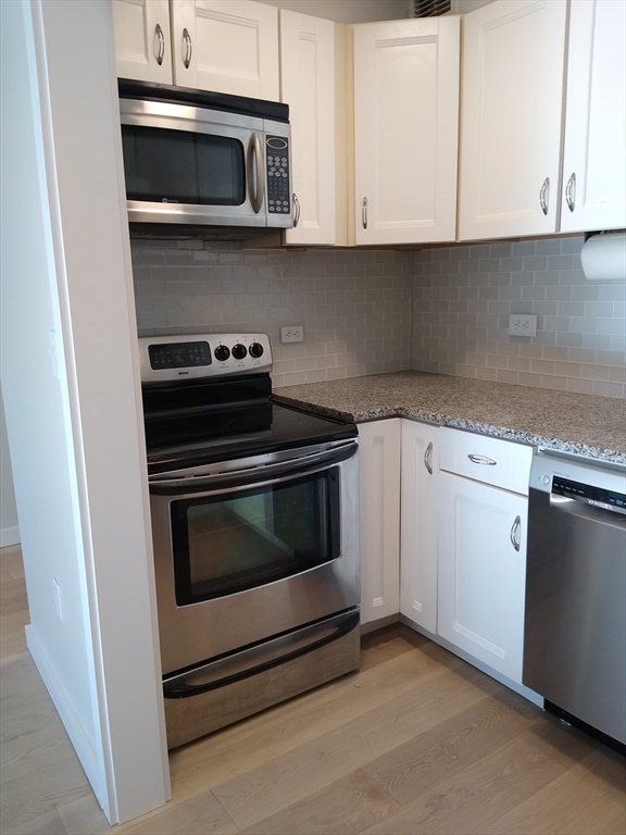 a kitchen with white cabinets and stainless steel appliances