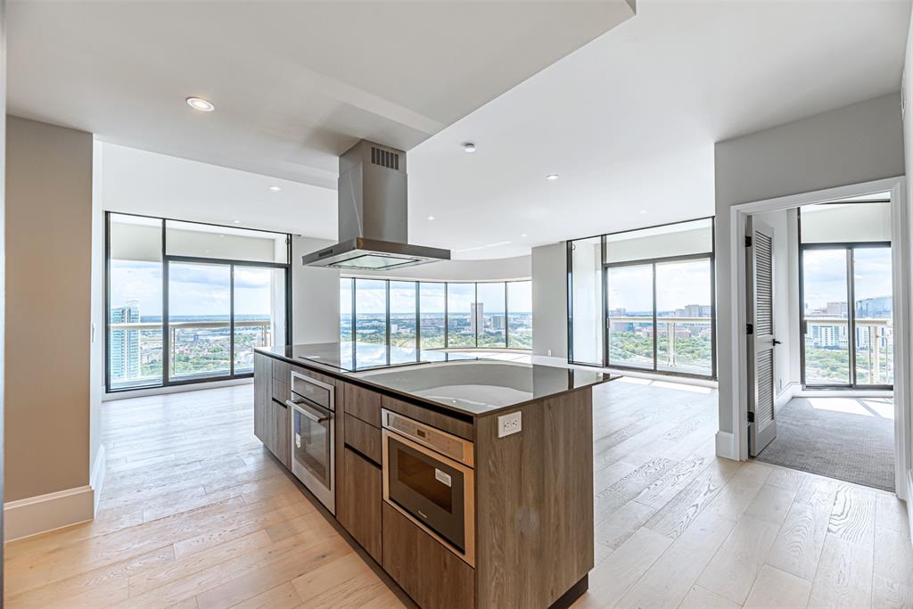 a kitchen with stainless steel appliances granite countertop a stove a sink and a large window with wooden floor