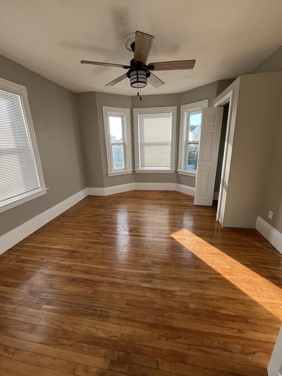 a view of empty room with wooden floor and fan