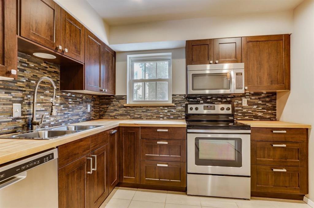 Kitchen with wooden counters, appliances with stainless steel finishes, tasteful backsplash, sink, and light tile patterned floors