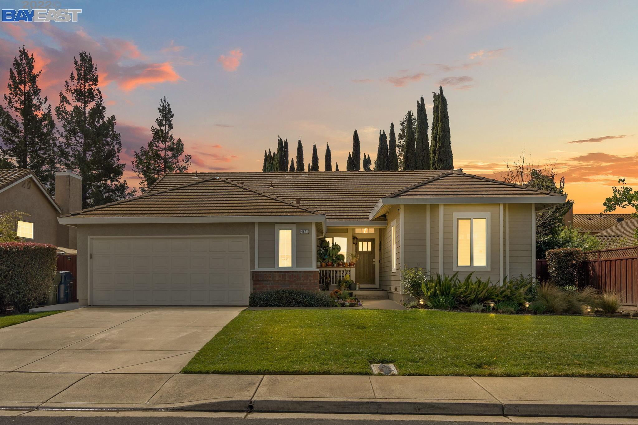 a front view of a house with a yard and trees