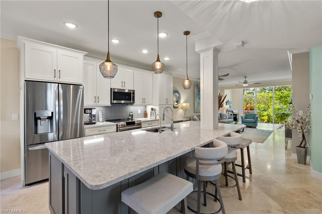 Kitchen with sink, white cabinets, stainless steel appliances, and decorative light fixtures