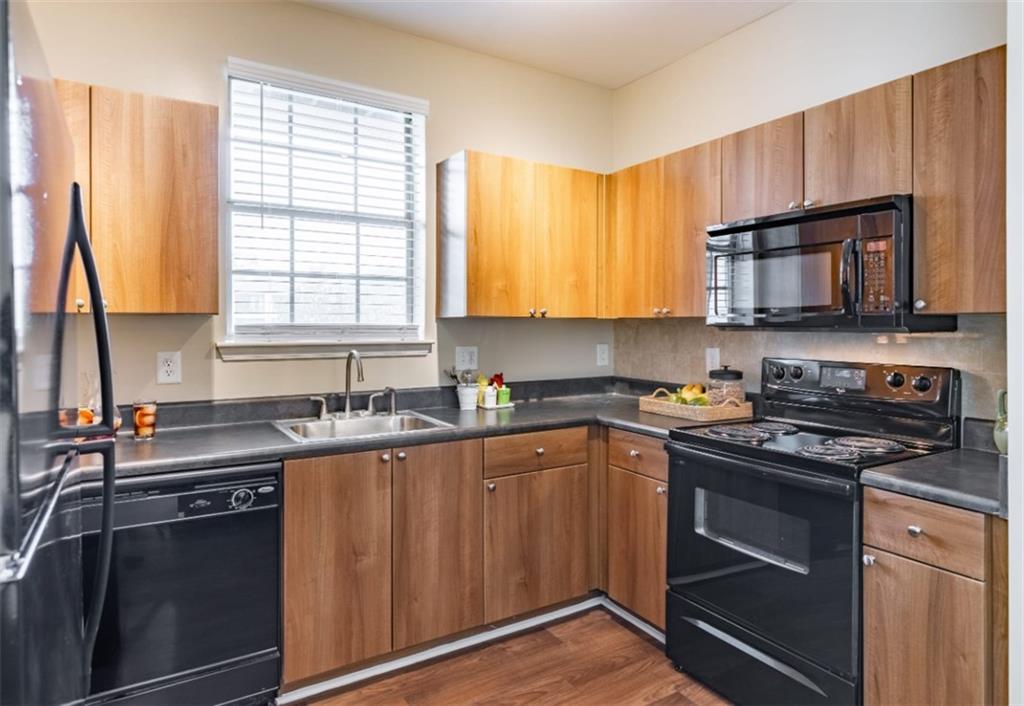 a kitchen with stainless steel appliances a sink a stove a microwave cabinets and a window