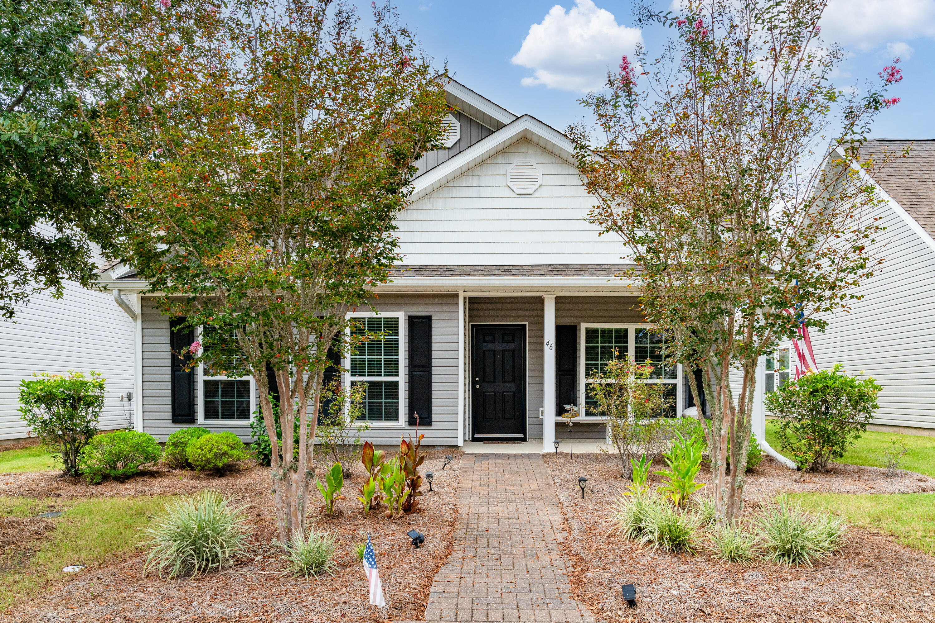 a front view of a house with a yard and potted plants