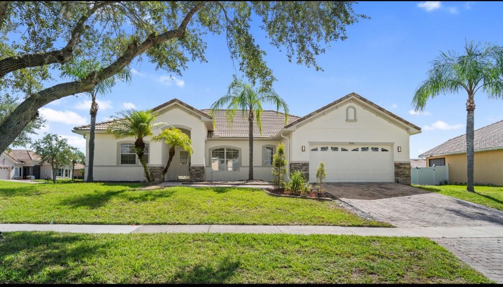 a view of a house with a yard and palm trees