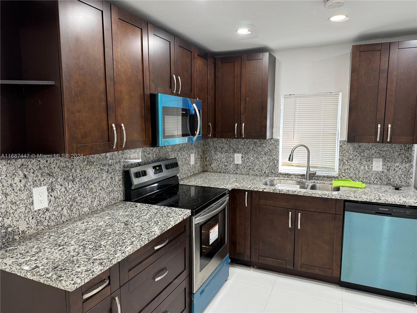 a kitchen with stainless steel appliances granite countertop wooden cabinets and a sink