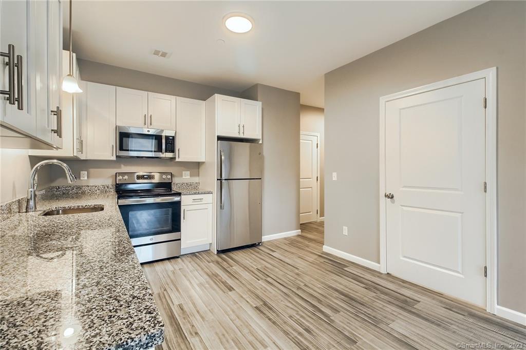 a kitchen with granite countertop white cabinets and stainless steel appliances