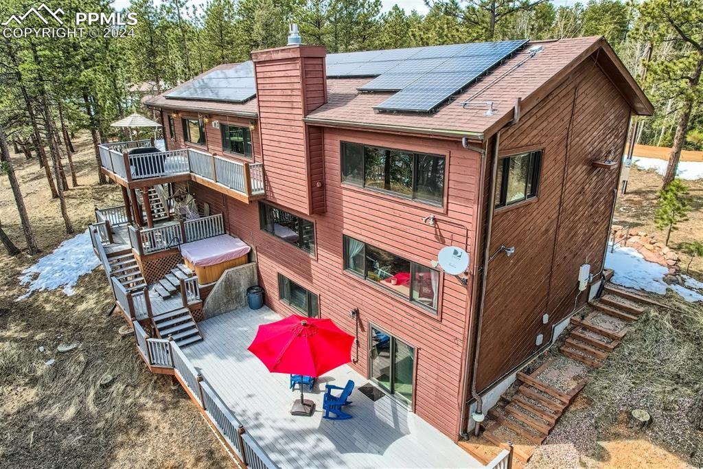 Rear view of house with solar panels and a wooden deck