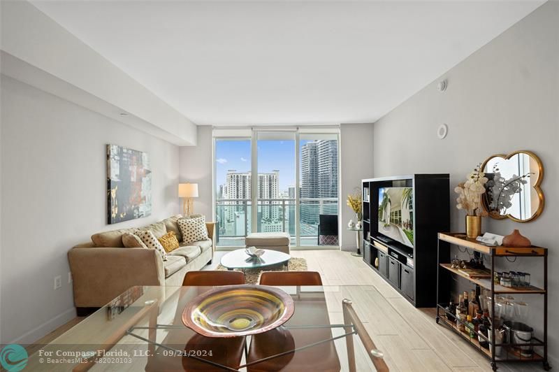 a living room with furniture a flat screen tv and floor to ceiling window