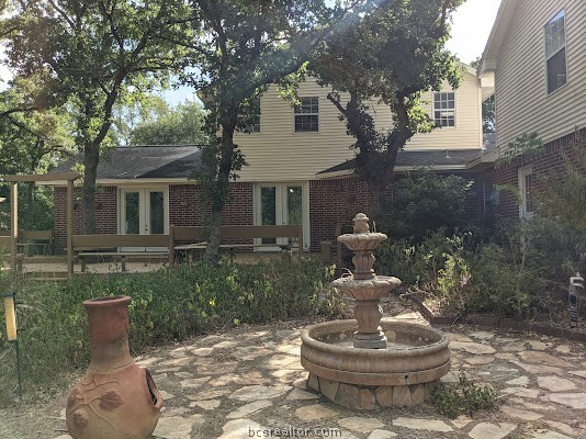 a front view of a house with a yard fountain and large tree